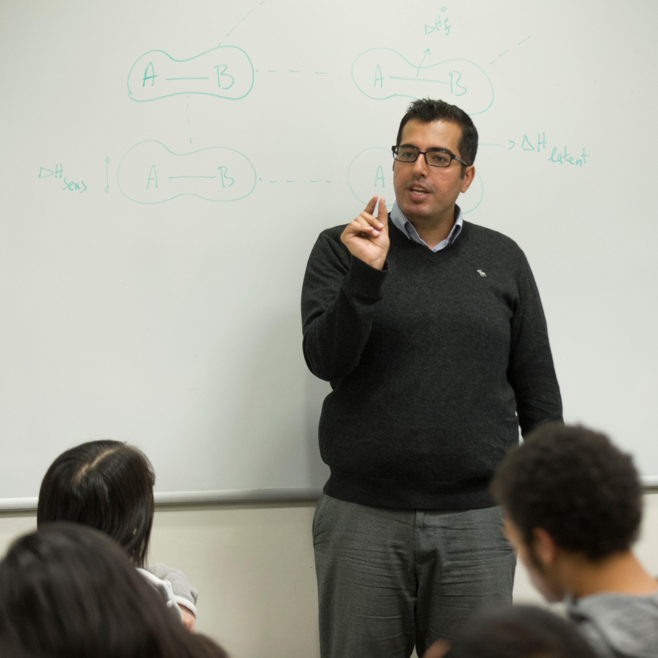 Instructor gestures at the front of a classroom