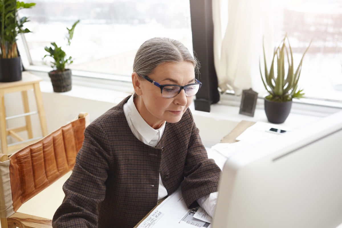 Woman working at her laptop in front of a sunny window