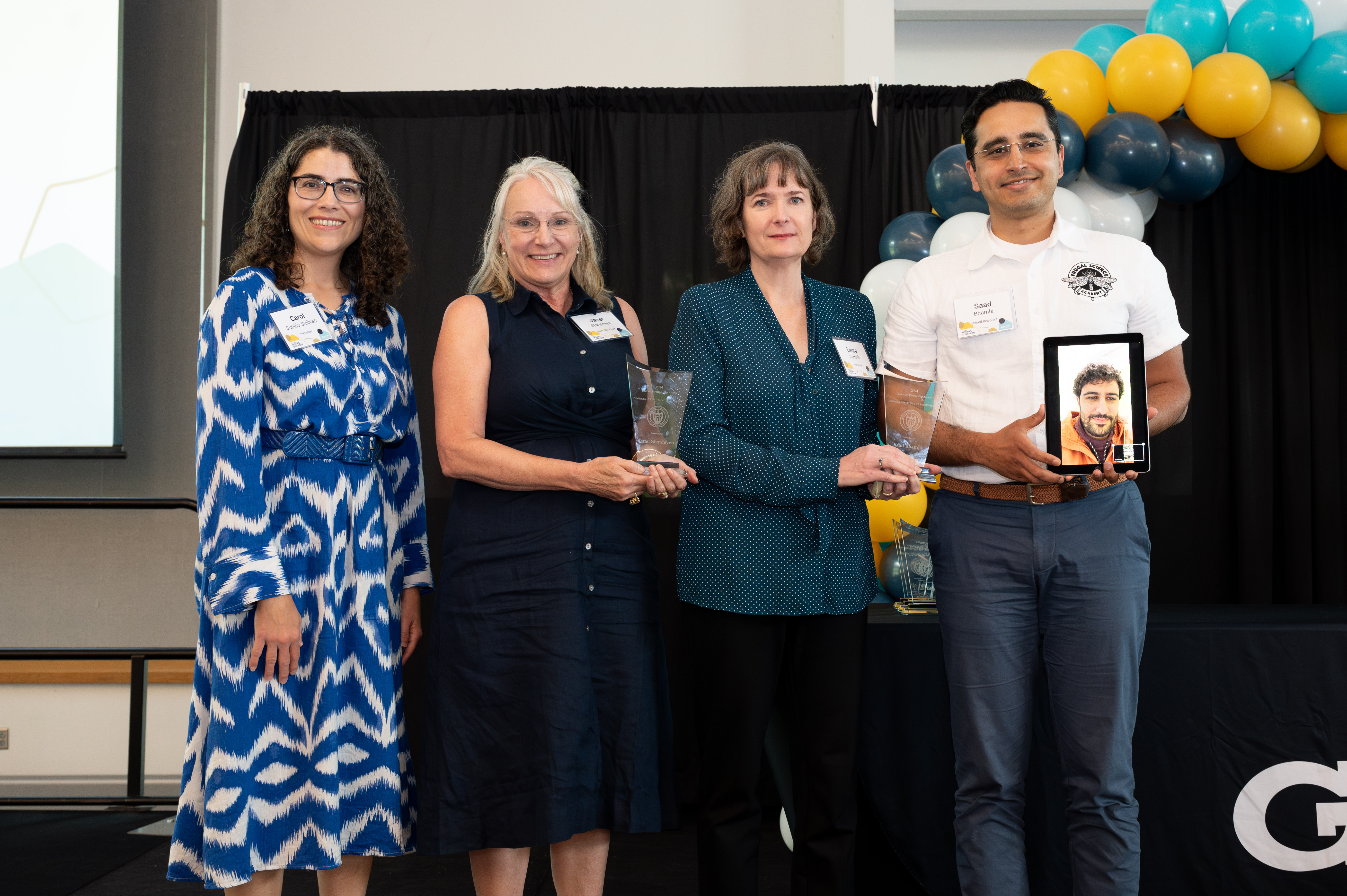 Janet Standeven, Saad Bhamla, and Elio Chalita (on the tablet) receive the Educational Partnership award during the Faculty and Staff Honors Luncheon 2024.