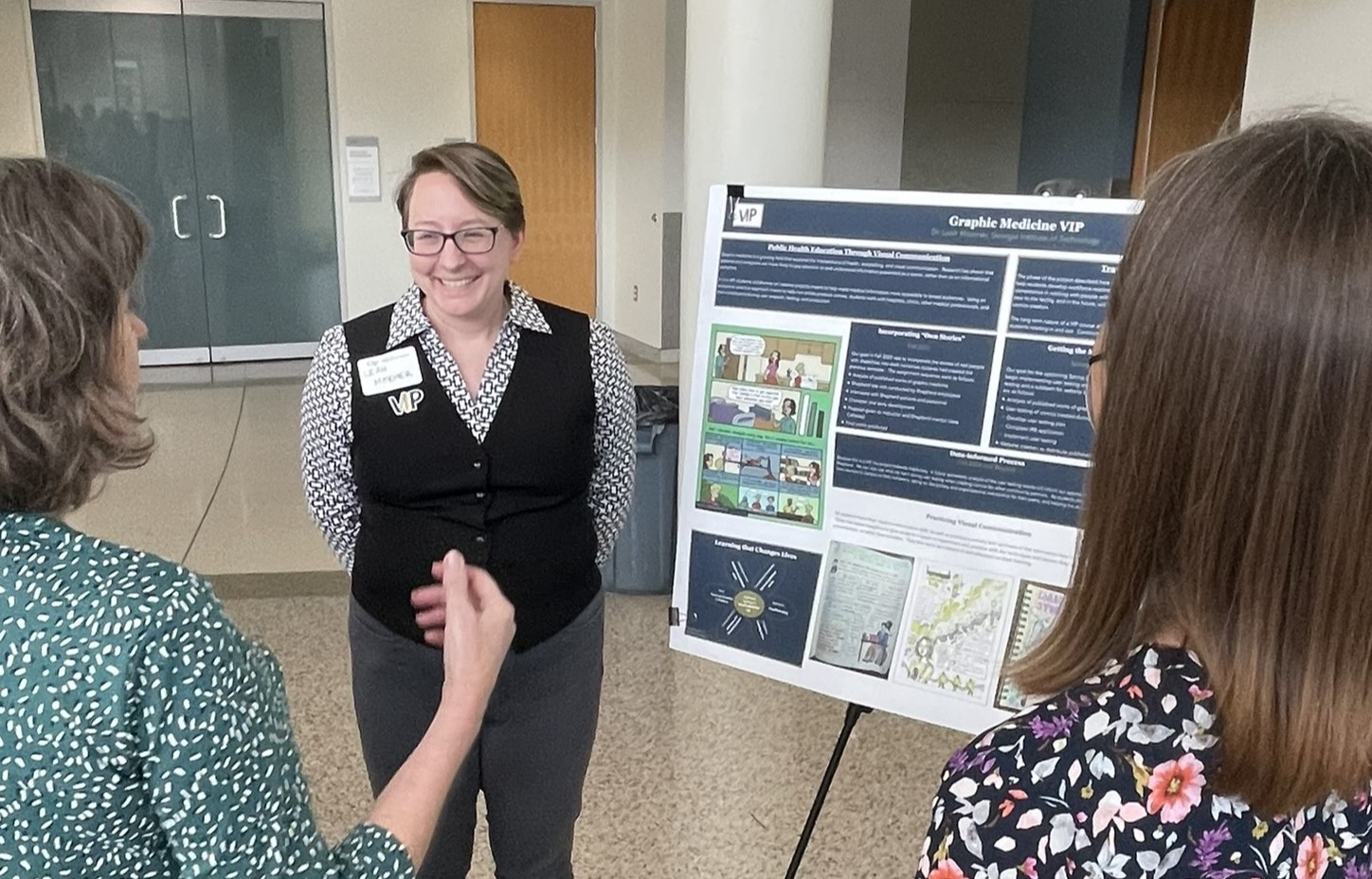 Three women standing near research poster